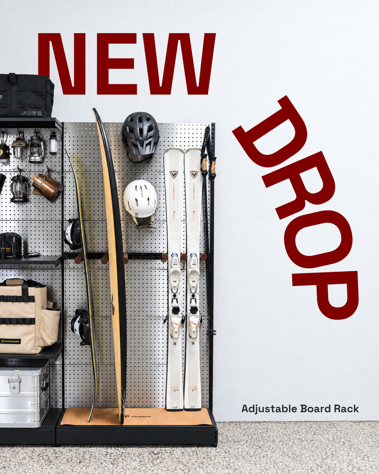A PegGrid display with skis and outdoor accessories beside red NEW DROP lettering promoting the Adjustable Board Rack.