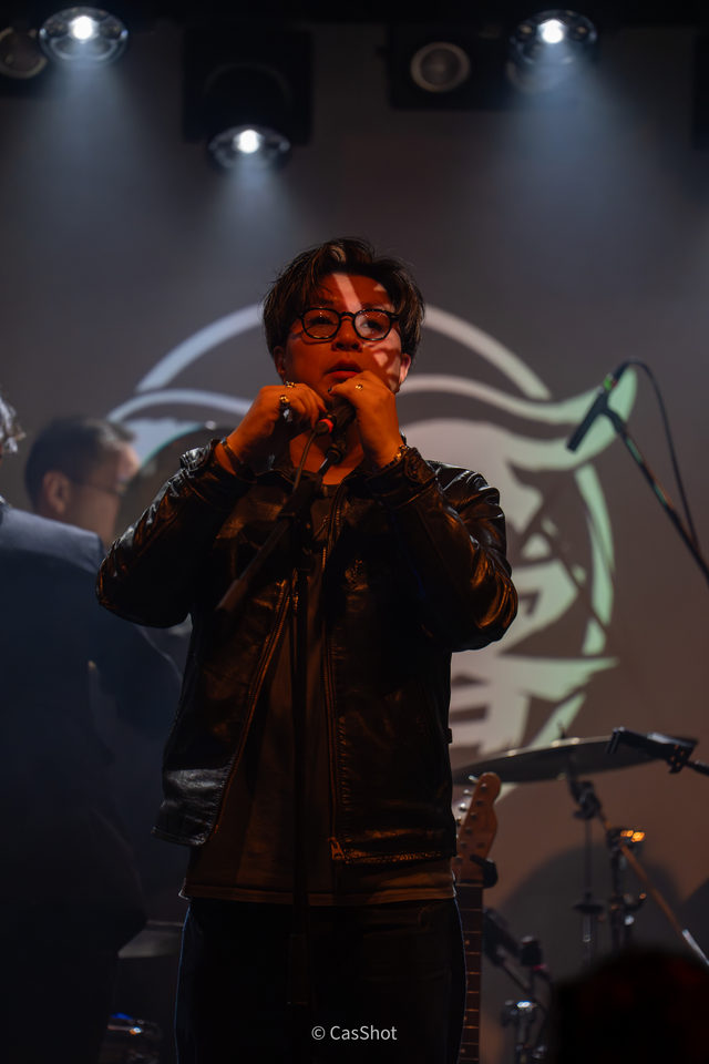 A singer holding a microphone beneath stage lights